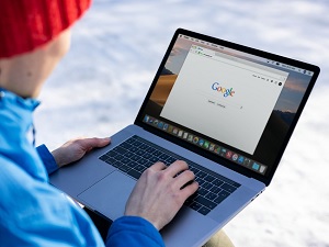person with a red hat on looking at an open laptop with the google screen