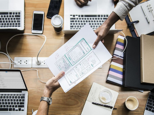 Three business people working at a desk on a project. Managed IT services