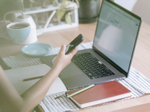 women working at desk with a open laptop papers laying on desk