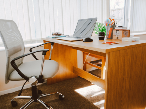 wooden desk with open laptop and a desk chair