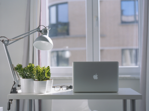 Apple Laptop sitting on desk with lamp 