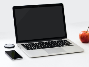 open laptop on a desk with an apple and cellphone